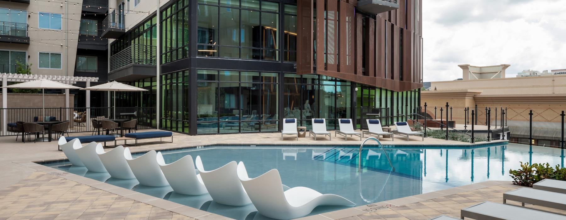 a building with a pool and chairs in front of it