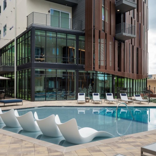 a building with a pool and chairs in front of it
